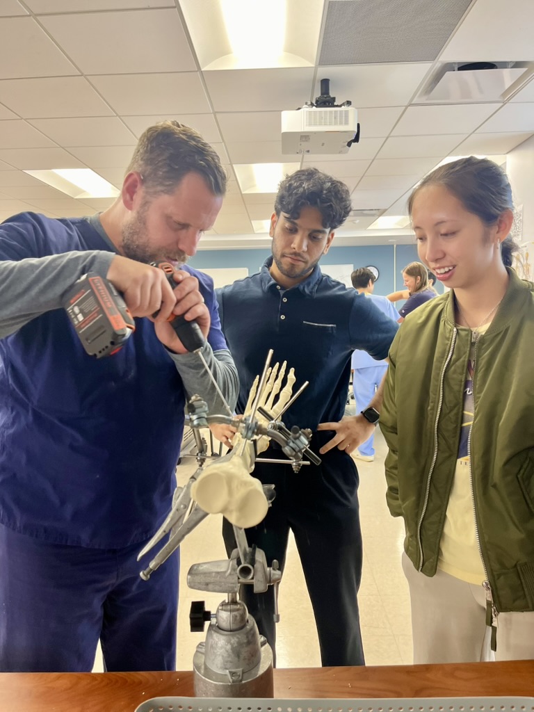 Dr. August Funk demonstrates the use of orthopedic surgery devices used in external fixation procedures as medical students Sajan Goyal (center), Sophia Manlapit (right) observe.&amp;amp;amp;amp;amp;amp;amp;amp;Acirc;&amp;amp;amp;amp;amp;amp;amp;amp;nbsp;