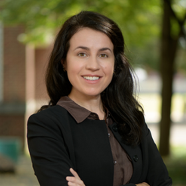 outdoor head shot of Yvonne Schleife smiling with arms folded in front of her