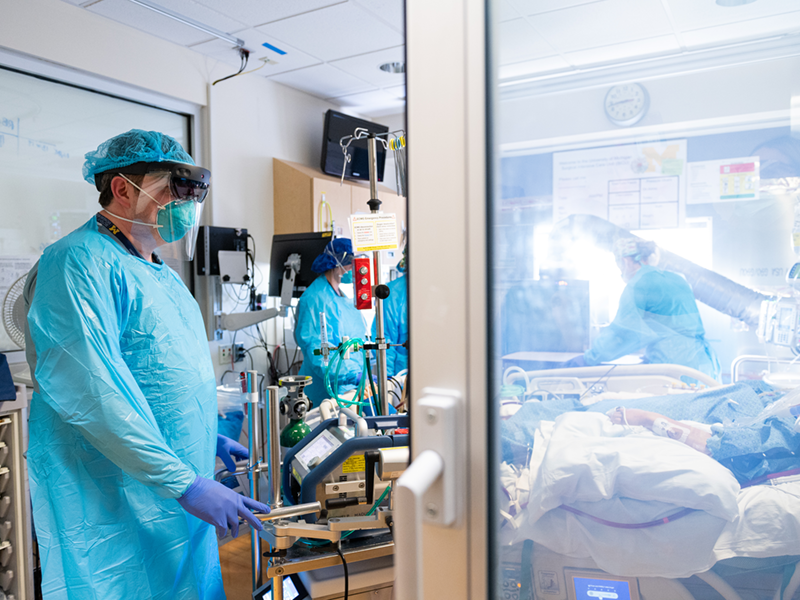 Dr. Mark Cohen exams a COVID-19 patient using a Microsoft HoloLens2 headset while others participate in patient rounds from another location. Photos by Michigan Photography