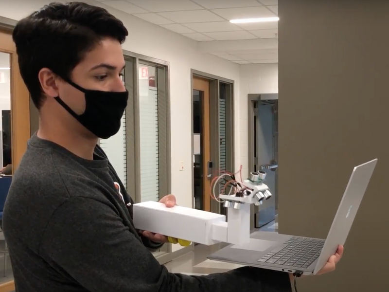 Bioengineering student Benjamin Salzberg demonstrates the prototype of the EYES ultrasonic scanning device developed by a team including Carle Illinois College of Medicine students Emily Smith, Katy Stauffer, and Natalie Ramsy.