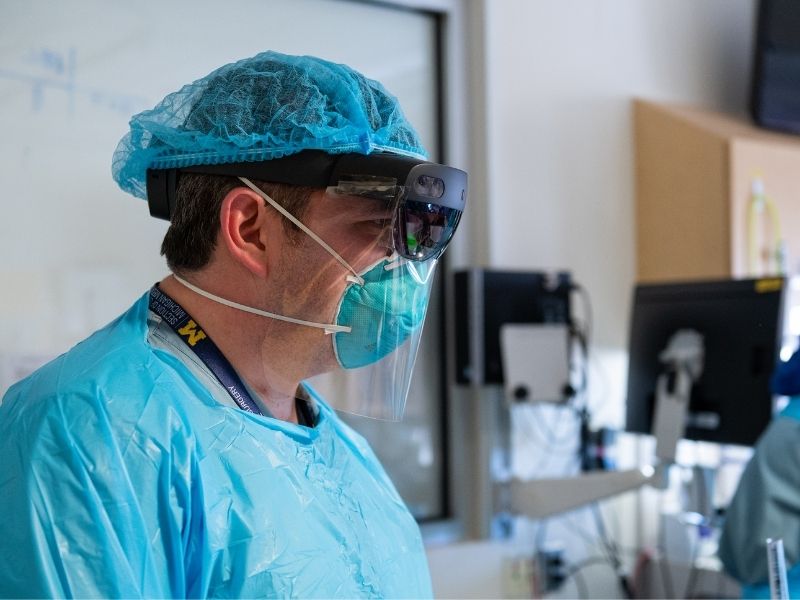 Dr. Mark Cohen exams a COVID-19 patient using a Microsoft HoloLens2 headset while others participate in patient rounds from another location. Photos by Michigan Photography