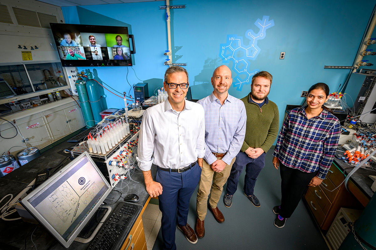 <em>IIllinois researchers led an international team that combined powerful AI and a molecule-making machine to find the best conditions for automated complex chemistry. Pictured, from left: University of Illinois chemistry professor Martin D. Burke, materials science and engineering professor Charles M. Schroeder, graduate student Nicholas Angello and postdoctoral researcher Vandana Rathore. Pictured on the screen behind them are international collaborators, led by professors Bartosz A. Grzybowski and Al&aacute;n Aspuru-Guzik.</em><br><em>Photo by Fred Zwicky</em>