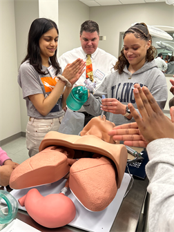 <em>Med student Nama Naseem (left) and CI MED Executive Vice Dean Dr. Gregory Polites (middle) cheer on a student as they learn how to intubate a patient.&nbsp;</em>